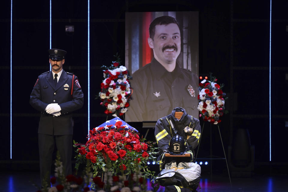 A photograph of firefighter-paramedic Adam Finseth, 40, stands over his gear during a memorial service for Finseth and Burnsville police officers Paul Elmstrand, 27, and Matthew Ruge, 27, at Grace Church in Eden Prairie, Minn., on Wednesday, Feb. 28, 2024. (Aaron Lavinsky/Star Tribune via AP, Pool)