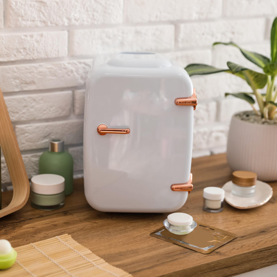 Mini fridge on countertop next to skincare products