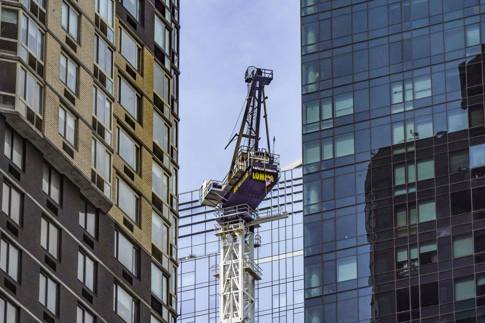 A hi-rise construction site crane, center, is left standing without its extension arm, after it broke away during a fire yesterday and plummeted to the street, Thursday July 27, 2023, in New York. (AP Photo/Bebeto Matthews)