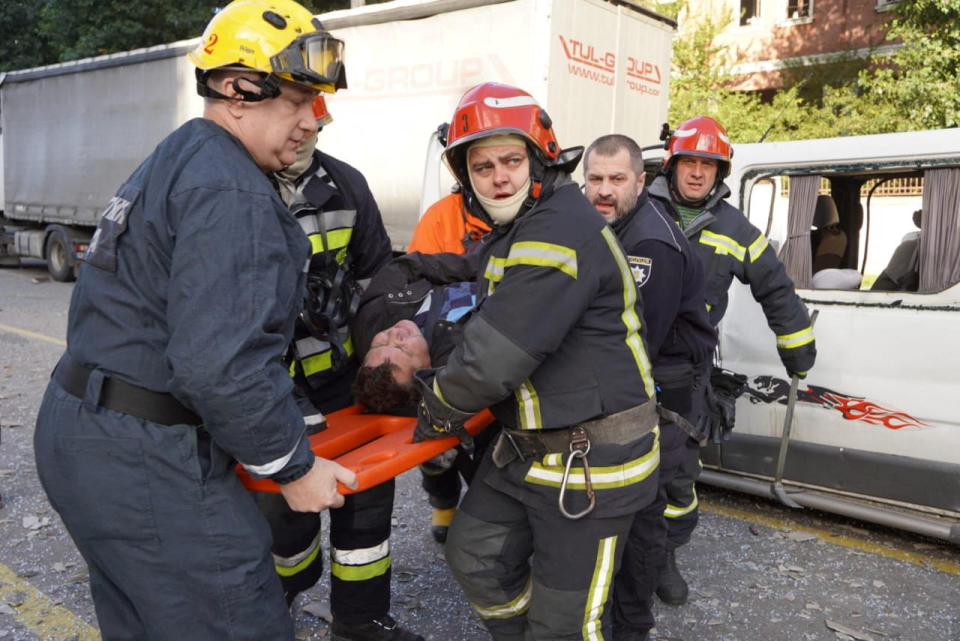 Six rescuers carry an injured man. 