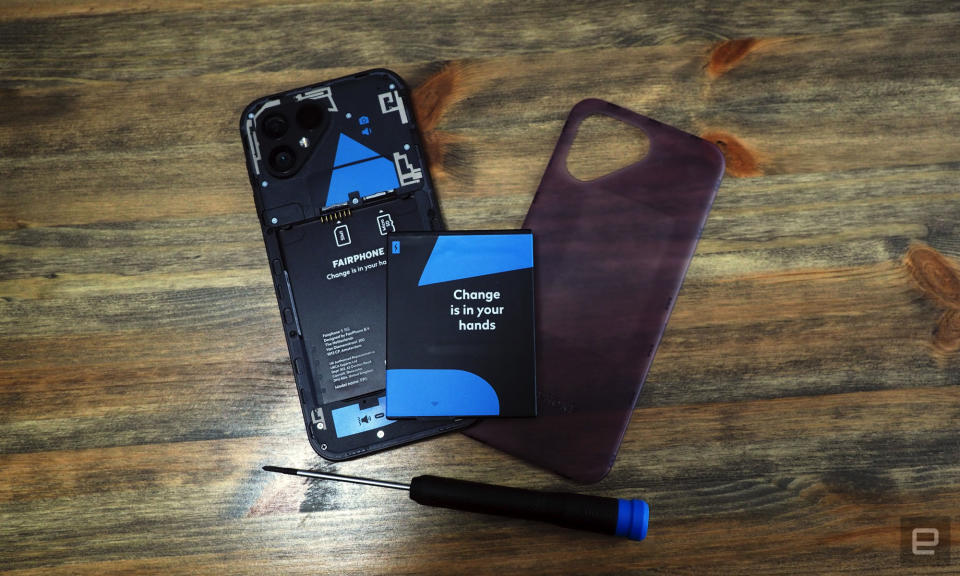 Image of the Fairphone 5 with its rear cover and battery open above a screwdriver.