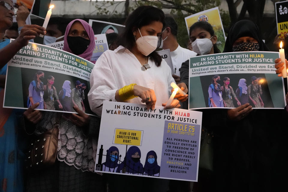 FILE - People hold placards and candles in Bengaluru, India, during a protest against banning Muslim girls from wearing the hijab in educational institutions in southern Karnataka state, Feb. 19, 2022. The furor began in January when staffers at a government-run junior college in Udupi, a coastal city in Karnataka, began refusing admission to girls who showed up in a hijab, saying they were violating the uniform code. (AP Photo/Aijaz Rahi, File)