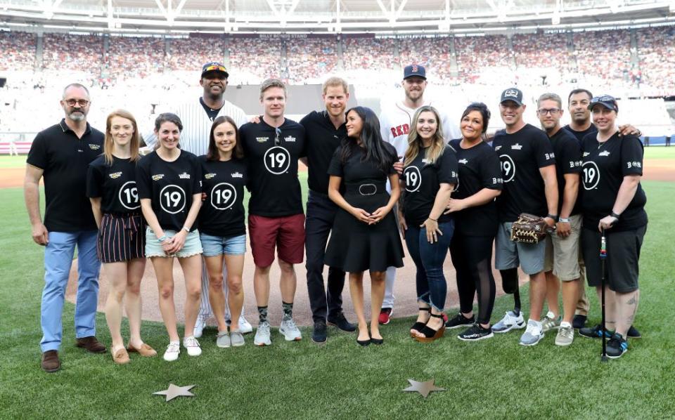 Prince Harry puts his arm around Meghan Markle as they pose for photos.