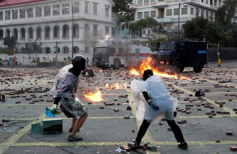 Anti-government protesters throw molotov cocktails towards police vehicles during clashes, outside Hong Kong Polytechnic University