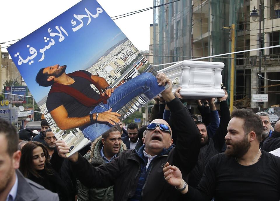 A mourner holds a portrait of Elias Wardini, a Lebanese man who was killed in the New Year's Eve Istanbul nightclub attack, as others carry his coffin during his funeral procession, at a church in Beirut, Lebanon, Tuesday, Jan. 3, 2017. The gunman killed 39 people, most of them foreigners, including three Lebanese citizens, at the Istanbul nightclub. Arabic on the picture reads, " Angel of al-Ashrafiyeh." (AP Photo/Hussein Malla)