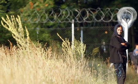 A migrant woman from Afghanistan stands near a fence after she crossed Hungary's border illegally near Asotthalom on June 29, 2015. REUTERS/Laszlo Balogh