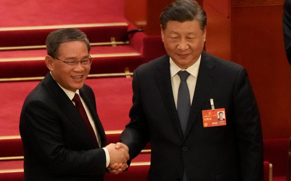 Newly elected Premier Li Qiang at left shakes hands with Chinese President Xi Jinping - AP Photo/Mark Schiefelbein
