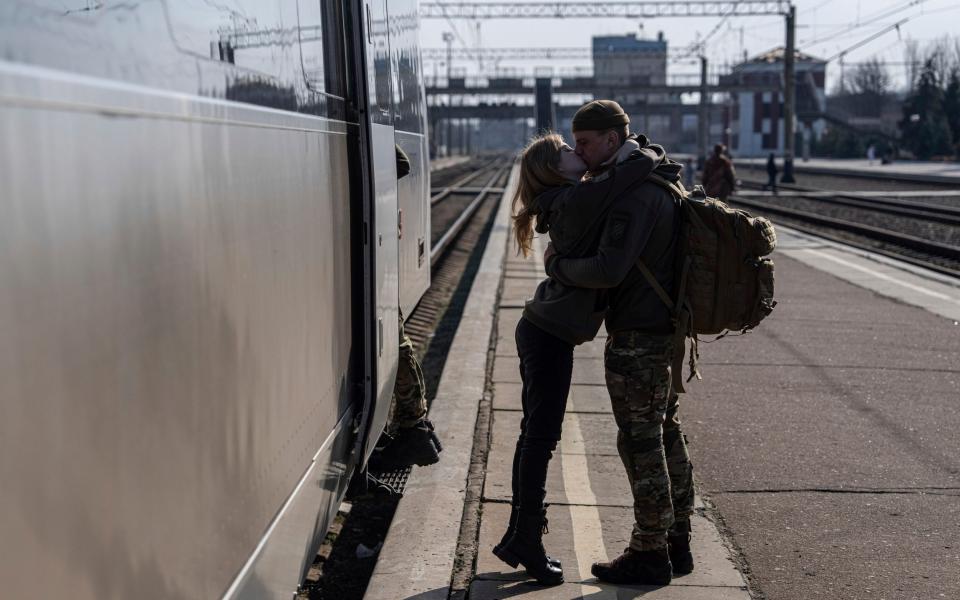 A Ukrainian serviceman kisses his partner at the train station in Kramatorsk - Evgeniy Maloletka/AP