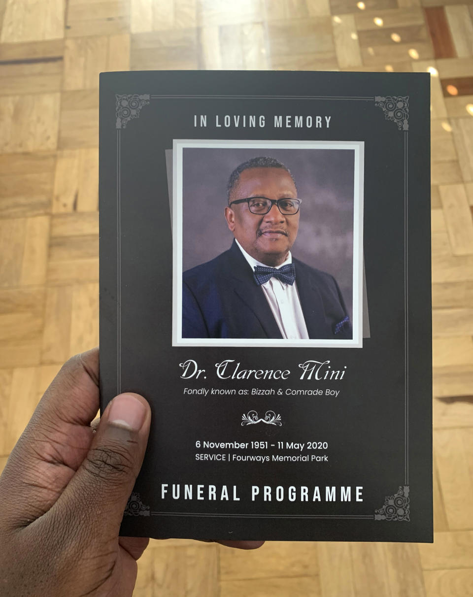 This Wednesday, June 10, 2020 photo provided by Yandi Mini shows him holding the funeral programme of his father, Dr. Clarence Mini at his Johannesburg home. Clarence Mini, a South African activist and doctor who died of COVID-19 spent his life fighting apartheid, the government's denial of HIV/AIDS and rampant corruption. Loved ones say Mini knew the odds were against him but he was committed to what he believed was right. He died in May at age 69. (Yandi Mini via AP)