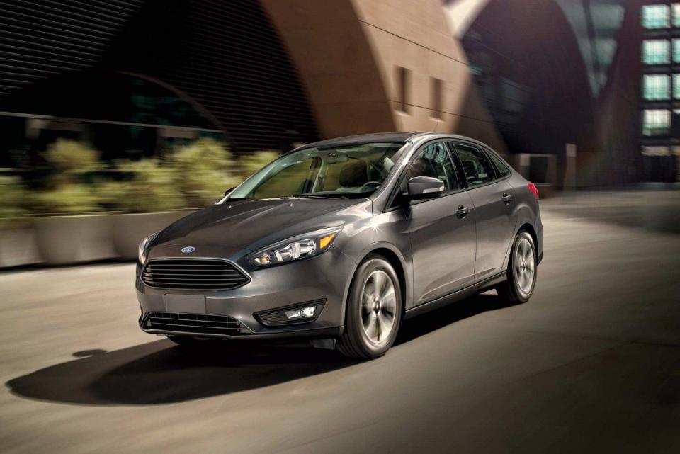 A gray Ford Focus on a street in front of a building