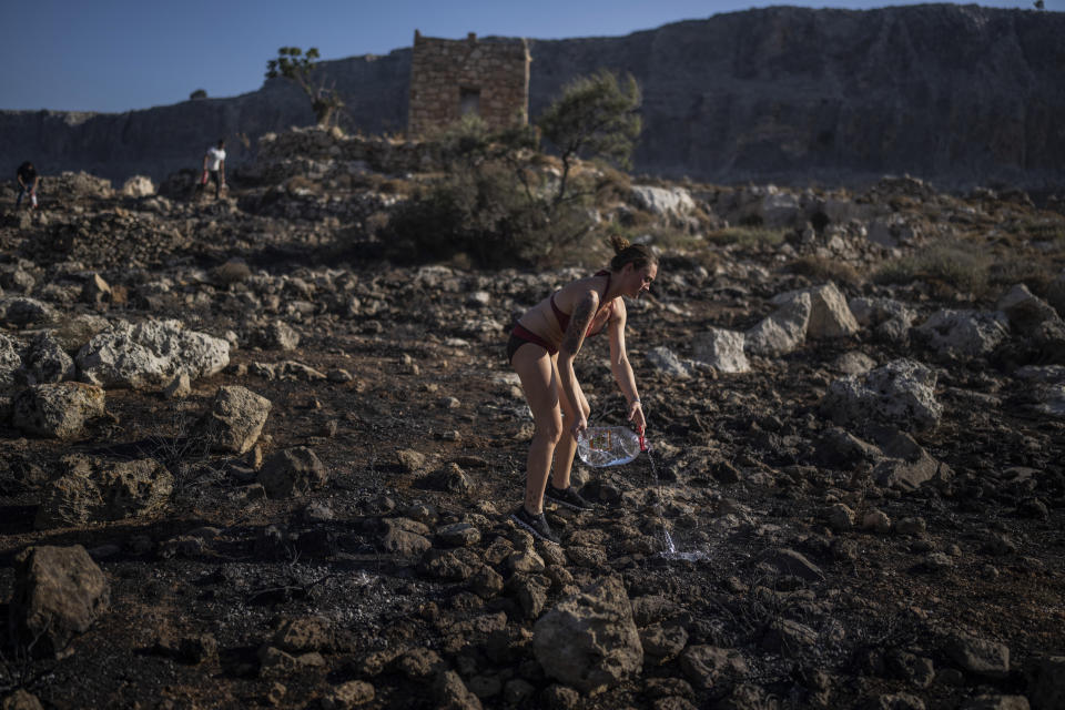 FILE - Jaquelin Stocklein from Germany drops water to a burnt area during a wildfire near the seaside resort of Lindos, on the Aegean Sea island of Rhodes, southeastern Greece, on July 24, 2023. Greece’s resort island of Rhodes is nursing its wounds after 11 days of devastating wildfires. (AP Photo/Petros Giannakouris, File)