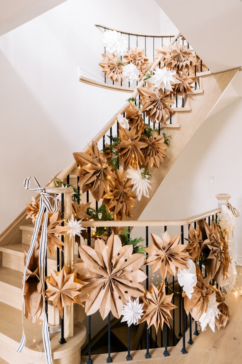 Staircase decorated with garland made of oversized paper bag snowflakes and fairy lights