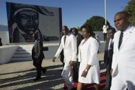 El presidente de Haití, Jovenel Moise, en el centro, y la primera dama, Martine Moise, caminan con el primer ministro Jean Henry Ceant mientras salen de la ceremonia de conmemoración del aniversario del asesinato del héroe de la independencia en Puerto Príncipe, el miércoles 17 de octubre de 2018. (AP Foto / Dieu Nalio Chery)