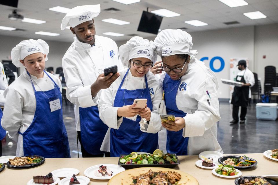 Jordyn McDonald, left, Chris Carter, Yostena Akladyous, and Iman Moses, all of Fraser High School, take photos of the dishes they made during Michigan ProStart program's Mise en Place Bootcamp at Sysco Detroit in Canton on Friday, Jan. 13, 2023.