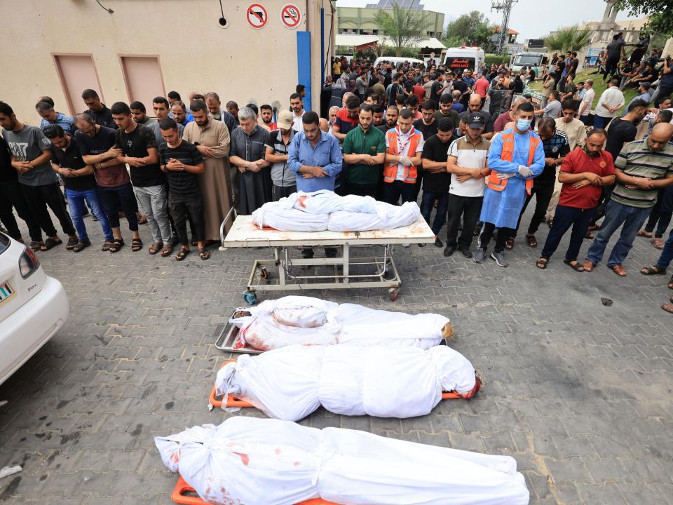 Palestinians pray over the bodies of people killed in an Israeli airstrike on the refugee camp of Jabalia in the Gaza Strip on October 9, 2023.