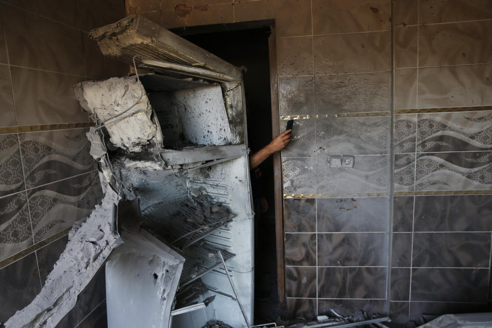 A local resident uses his mobile to take photos of the damages on a house, caused by a mortar fired from inside Syria, on the Turkish town of Akcakale, southeastern Turkey, Saturday, Oct. 12, 2019.Nobody got hurt by the attack.The owners of the house weren't home at the time of the attack. Turkey says its military offensive has taken central Ras al-Ayn, a key border town in northeastern Syria, and its most significant gain since its cross-border operation began against Syrian Kurdish fighters began. (AP Photo/Lefteris Pitarakis)