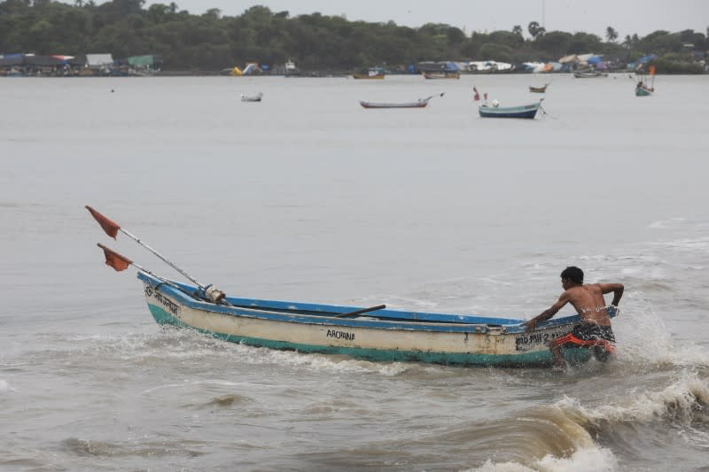 A fisherman pushes his boat to anchor it before cyclone Nisarga makes its landfall, in Mumbai