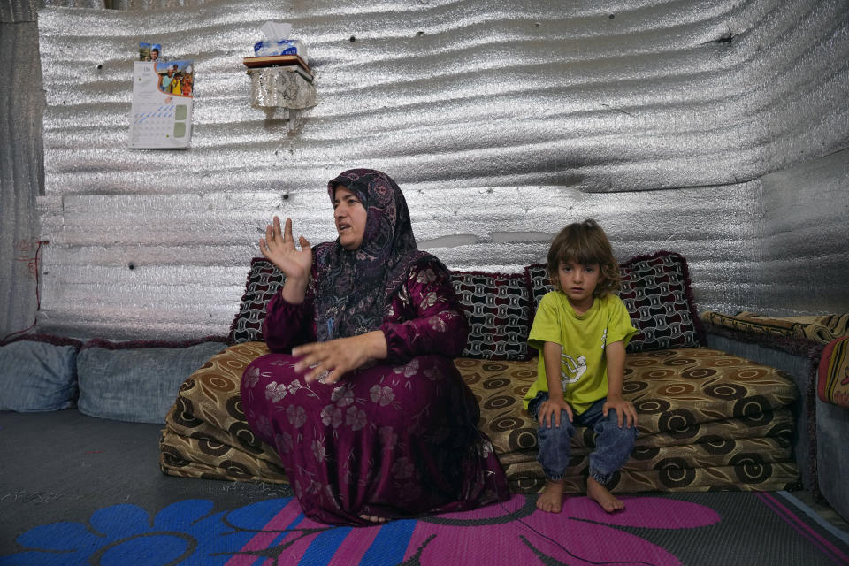 Syrian Fteim Al-Janoud speaks as her daughter Qamar sits next to her during an interview with The Associated Press inside her tent at a refugee camp in the town of Bar Elias, in Lebanon's Bekaa Valley, Tuesday, June 13, 2023. Aid agencies are yet again struggling to draw the world's attention back to Syria in a two-day donor conference hosted by the European Union in Brussels for humanitarian aid to Syrians that begins Wednesday. Funding from the conference also goes toward providing aid to some 5.7 million Syrian refugees living in neighboring countries, particularly Turkey, Lebanon and Jordan. (AP Photo/Bilal Hussein)
