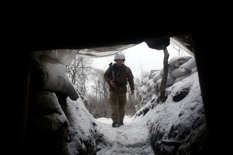 An Ukrainian Military Forces serviceman walks along a snow covered trench on the frontline with the Russia-backed separatists near Zolote village, in the eastern Lugansk region, on January 21, 2022. - Ukraine's Foreign Minister Dmytro Kuleba on January 22, 2022, slammed Germany for its refusal to supply weapons to Kyiv, urging Berlin to stop "undermining unity" and "encouraging Vladimir Putin" amid fears of a Russian invasion. (Photo by Anatolii STEPANOV / AFP)