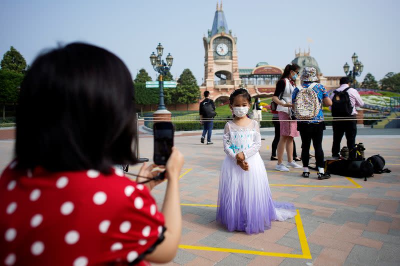 A girl wearing face mask poses for a picture at Shanghai Disney Resort as the Shanghai Disneyland theme park reopens following a shutdown due to the coronavirus disease (COVID-19) outbreak, in Shanghai