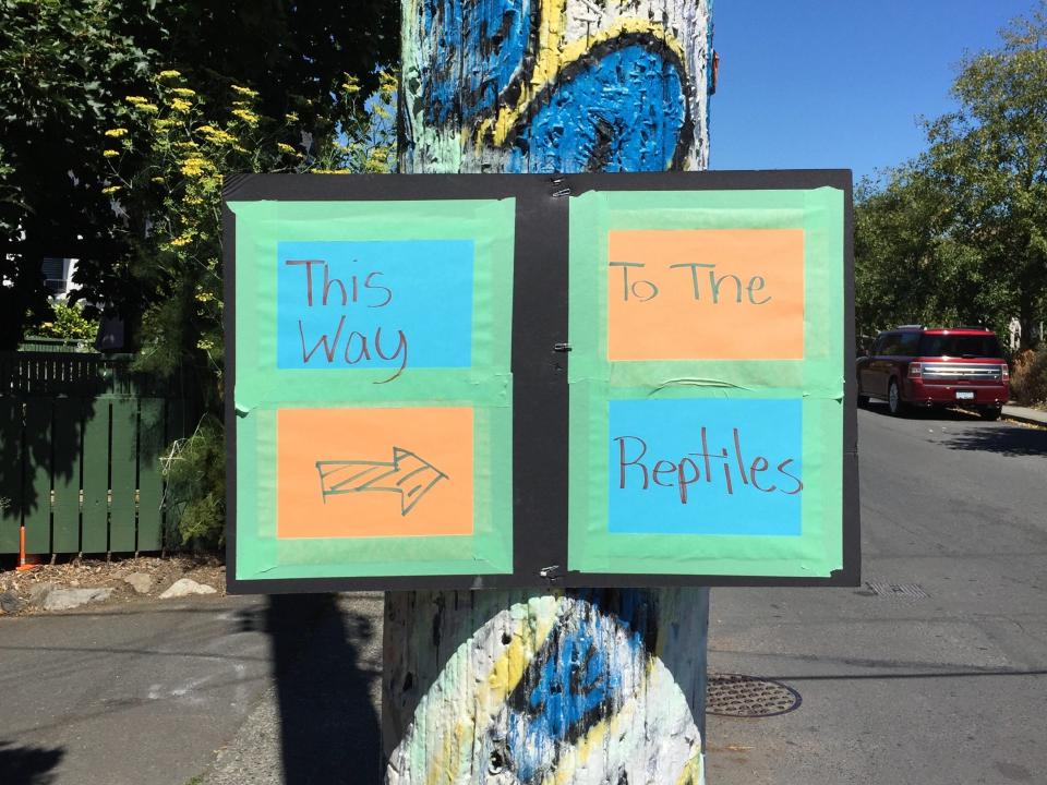 sign on a telephone pole that reads "this way to the reptiles"