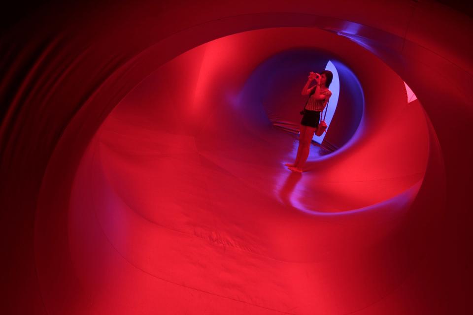 A woman takes a photograph inside Exxopolis, an inflatable walk-in luminarium at Grand Park in Los Angeles, California