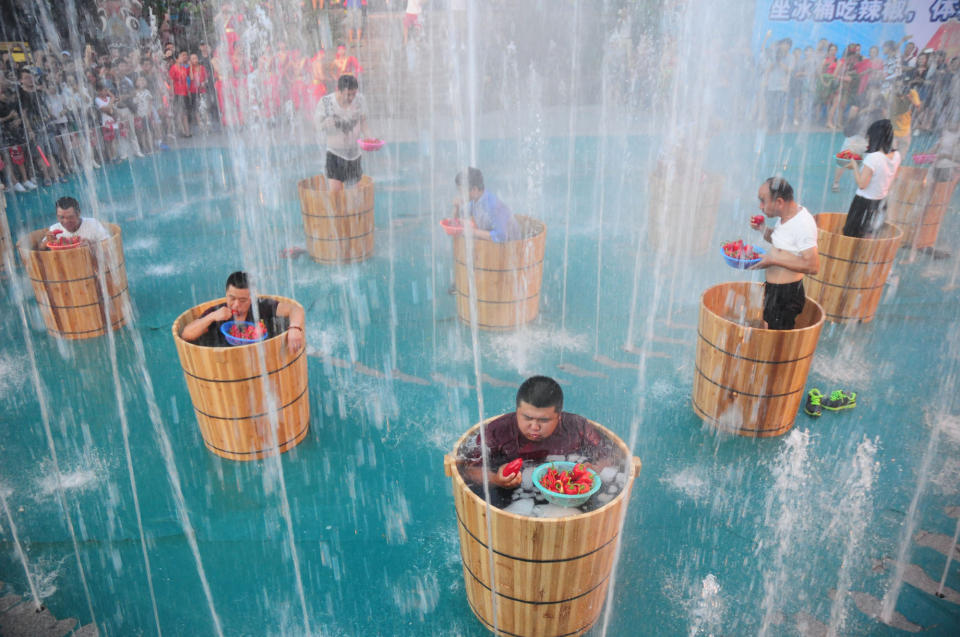 Tourists sitting in the ice buckets eat peppers in the fountain during a competition at Song Dynasty Town on July 20, 2016 in Hangzhou, Zhejiang Province of China.&nbsp;