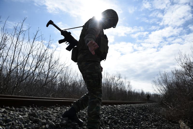 Greek soldiers walk on the railway tracks as they patrol next the Greek-Turkish border near the village of Marasia