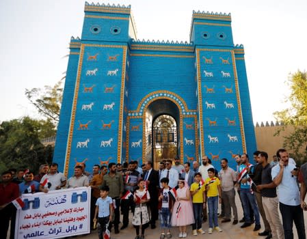 Iraqis celebrate after UNESCO designated ancient city of Babylon as World Heritage Site, in front of a replica of Ishtar gatee near Hilla