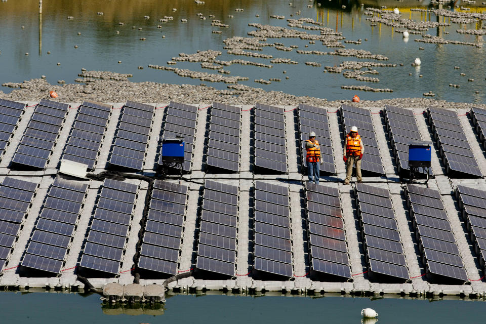 Workers stand on a floating island of solar panels on a pond at Los Bronces mine, about 65 kilometers (approximately 40 miles) from Santiago, Chile, Thursday, March 14, 2019. The 1,200-square-foot array of solar panels was inaugurated Thursday by Chilean Mining Minister Baldo Prokurica. Officials said that if the test is successful, the $250,000 plant could be expanded to cover 40 hectares, or nearly 100 acres. (AP Photo/Esteban Felix)