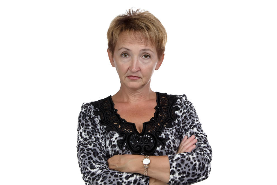 Woman with arms crossed, wearing a leopard print top with black trim, expressing disapproval