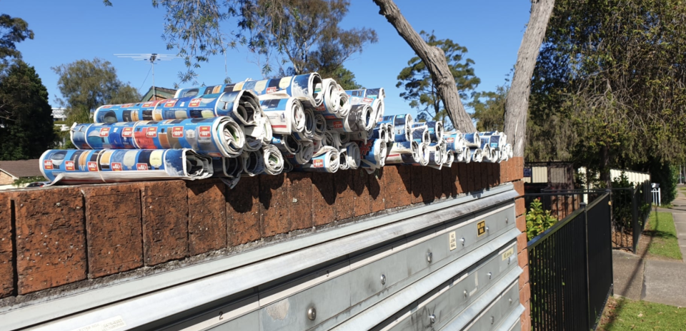 Photo shows piles of catalogues stacked on top of letterboxes in Sydney, NSW.