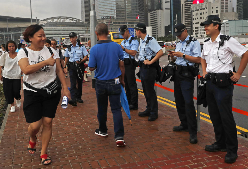 A woman shows thumps up to police officers during a counter-rally in support of the police in Hong Kong Saturday, July 20, 2019. A counter-rally in support of the police was held Saturday evening. Thousands of people under umbrellas and overcast skies filled a park in central Hong Kong. (AP Photo/Vincent Yu)