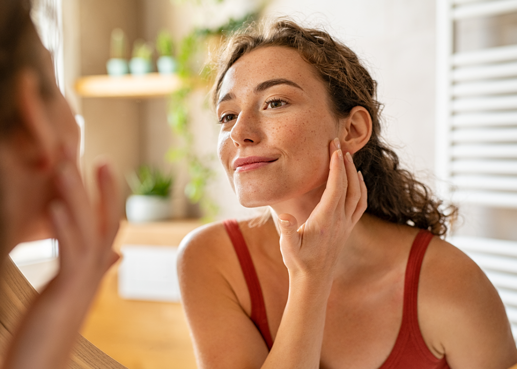 Woman looking at skin in mirror.