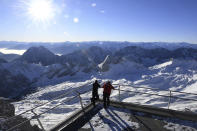 Two employees look out over the closed ski resort at the Zugspitze in Grainau, Germany, Monday, Nov 30, 2020. The skiing areas are prepared but due to the Corona pandemic restrictions skiing is not allowed at the area. (Angelika Warmuth/dpa via AP)