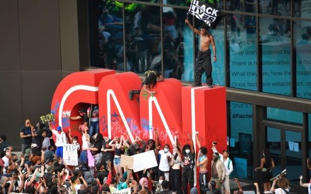 Demonstrators paint on the CNN logo during a protest, in Atlanta, in response to the death of George Floyd in police custody on Memorial Day in Minneapolis. - AP