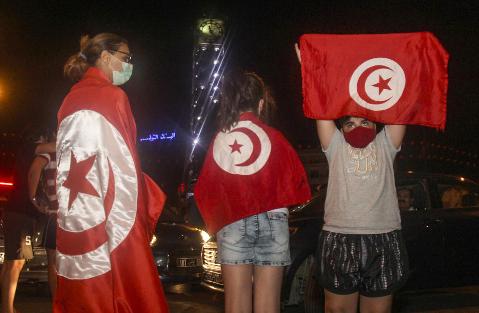 Demonstrators celebrate with Tunisian national flags during a rally after the president suspended the legislature and fired the prime minister in Tunis, Tunisia, Sunday, July 25, 2021. Protesters celebrated President Kais Saied's decision late Sunday night with shouts of joy, honking of horns and waving Tunisian flags. (AP Photo/Hedi Azouz)