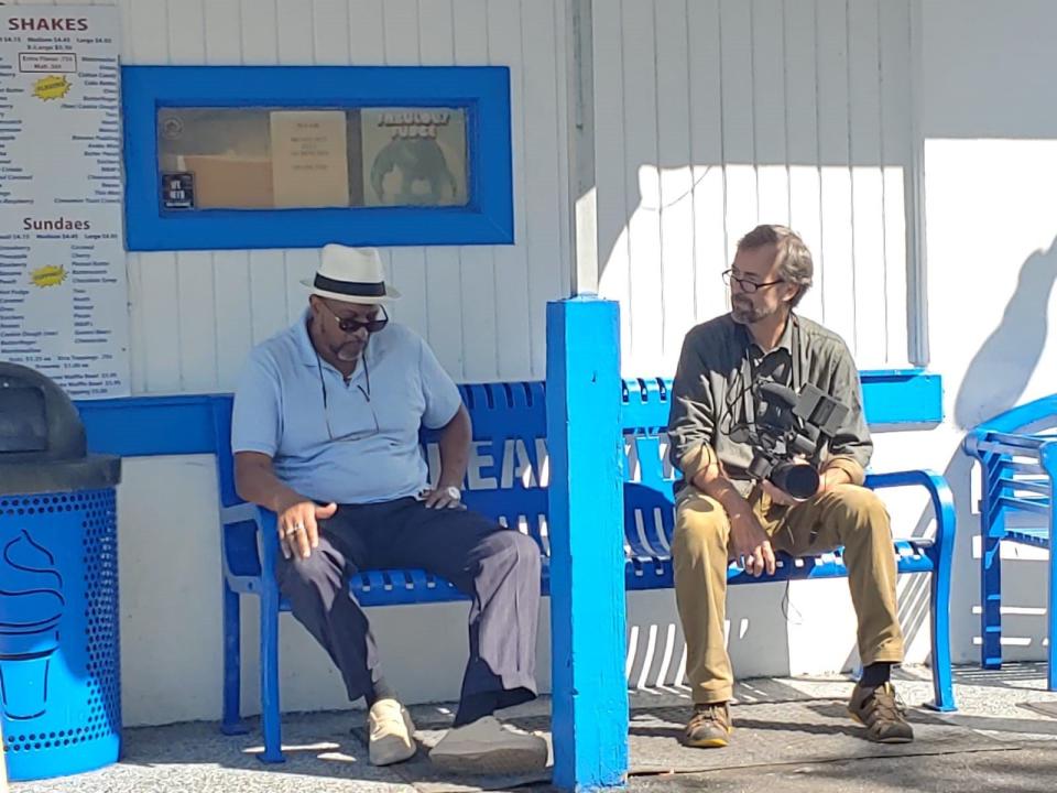 Donal Godfrey and filmmaker Hal Jacobs sit on a bench at the Dreamette during the filming of "Just Another Bombing?" The documentary tells the story of the KKK bombing Godfrey's home in 1964 because he was the first Black student at Lackawanna Elementary.