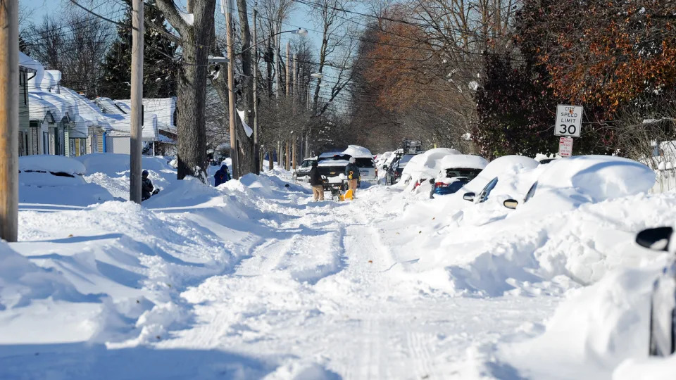 Pedestrians attempt to dig out cars after a snowstorm.