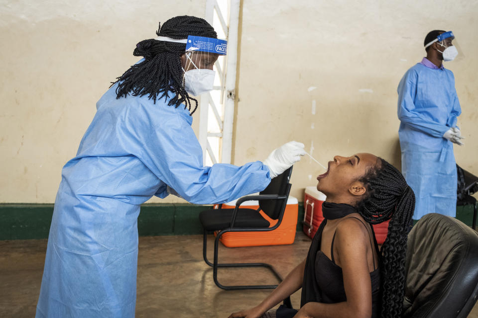 Ruth Irumva, right, is tested for COVID-19 at a testing center in the capital Kigali, Rwanda, Tuesday, July 28, 2020. Like many countries, Rwanda is finding it impossible to test each of its citizens for the coronavirus amid shortages of supplies but researchers there have created an innovative approach using an algorithm to refine the process of pooled testing that's drawing attention beyond the African continent. (AP Photo)