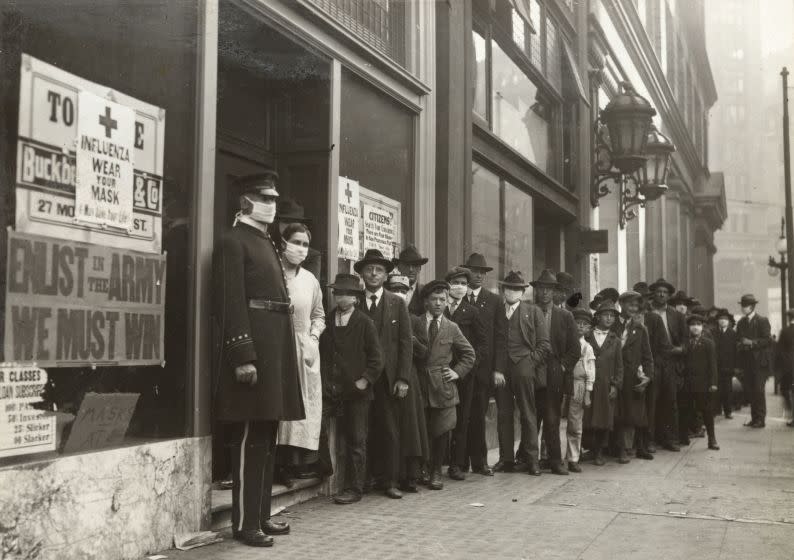 A handout picture provided by the California State Library shows people waiting in line to get flu masks on Montgomery Street in San Francisco, California, in 1918. Unlike Los Angeles, San Francisco stressed mask wearing, but not social distancing during the Spanish flu pandemic.