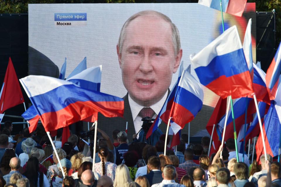 People watch on a large screen as Russian President Vladimir Putin speaks in Moscow on September 30, 2022.