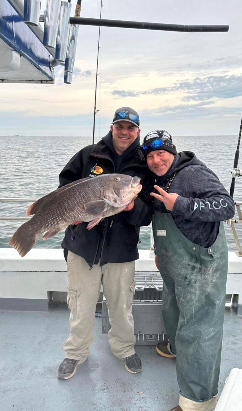 Thomas Fariello, left, holds up the 21-pound blackfish he caught fishing out of Cape May. Standing next to him is Anthony Emerick.