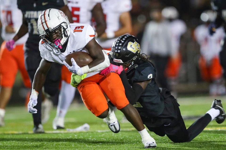 Lely Trojans running back Nino Joseph (13) is tackled by Golden Gate Titans safety Bradley Martino (2) during the second quarter of a district game at Golden Gate High School in Naples on Friday, Oct. 27, 2023.