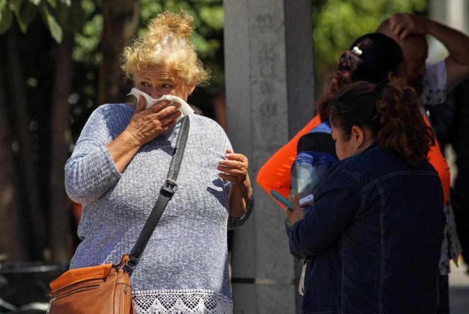 A woman covers her mouth trying to avoid the smell outside the Institute of Forensic Sciences