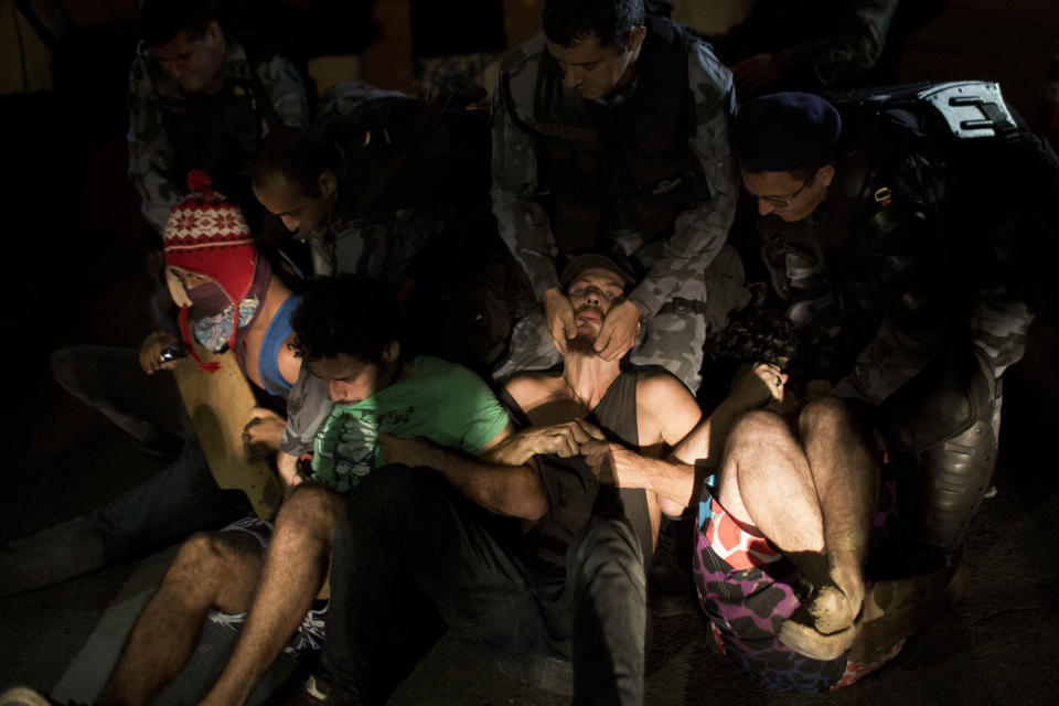 Supporters of the indigenous people who have been occupying the old Indian Museum are grabbed by riot police as they blocked the road outside the museum in Rio de Janeiro, Friday, March 22, 2013. The clash Friday is a bid to expel the group, some of whom have been squatting in the crumbling complex for years. The Indian museum has been at the center of a drawn-out legal battle between the several dozen Indians who've been living there for years and state and local authorities. Officials initially wanted to raze the complex as part of renovations ahead of Brazil's 2014 World Cup. (AP Photo/Felipe Dana)