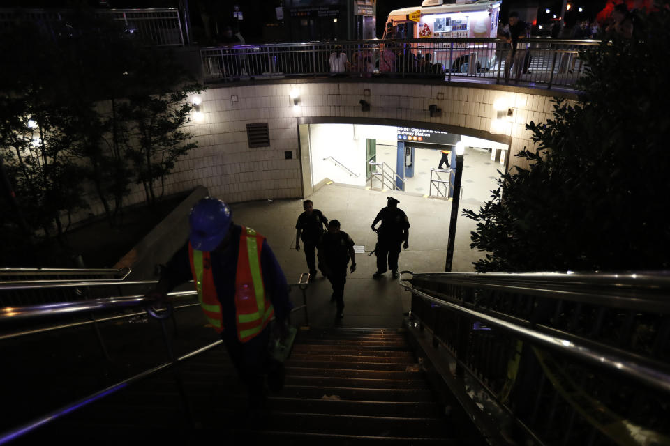 Police officers stand at the entrance to a closed subway station during a power outage Saturday, July 13, 2019, in New York. (AP Photo/Michael Owens)