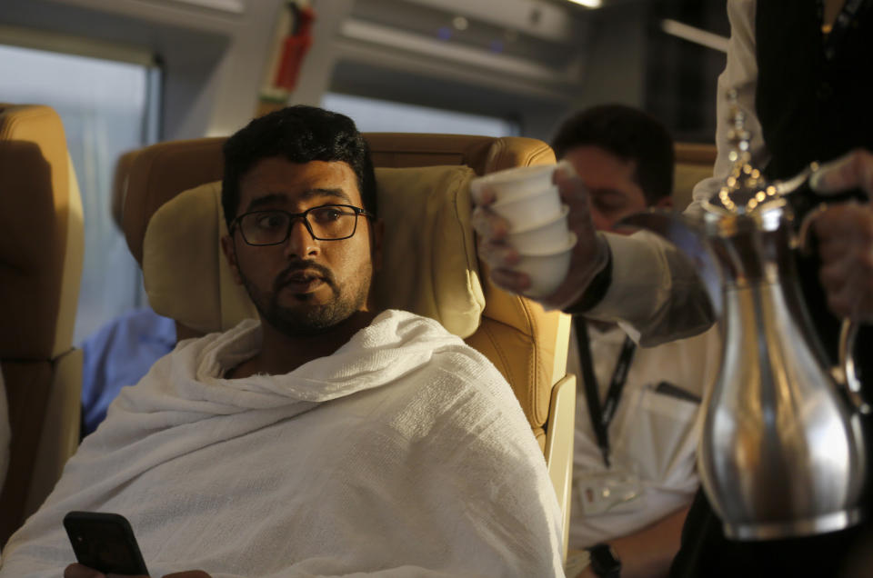 A Pilgrim on his way to Mecca is served Arabic coffee on the Haramain High-Speed Railway train in the holy city of Medina, Saudi Arabia, Thursday, Aug. 8, 2019. Hundreds of thousands of Muslims have arrived in the kingdom to participate in the annual hajj pilgrimage, which starts Friday, a ritual required of all able-bodied Muslims at least once in their life. (AP Photo/Amr Nabil)