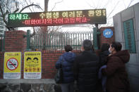 Parents watch their children head to the college entrance exam in front of a high school in Seoul, South Korea, Thursday, Dec. 3, 2020. South Korean officials urged on Wednesday people to remain at home if possible and cancel gatherings as about half a million students prepare for the crucial national college exam. The electric board reads: "Welcome to students." (AP Photo/Ahn Young-joon)