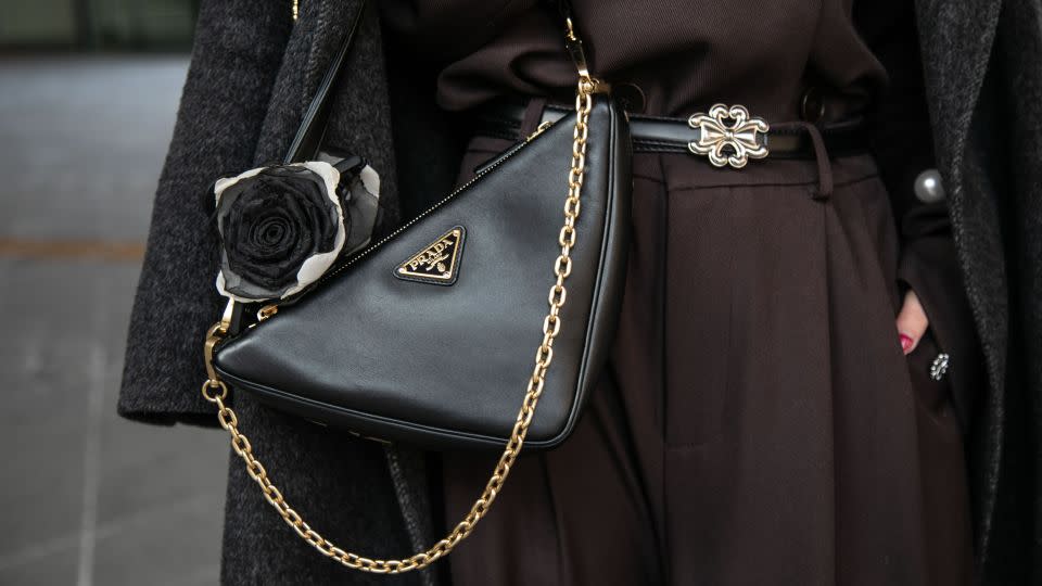 Wu Qin Qin wears a black Prada triangle bag over a black 4mile coat. - Jean Chung/Getty Images